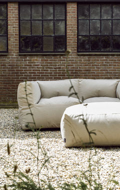 Een loungebank en hocker buiten geplaatst op het grind