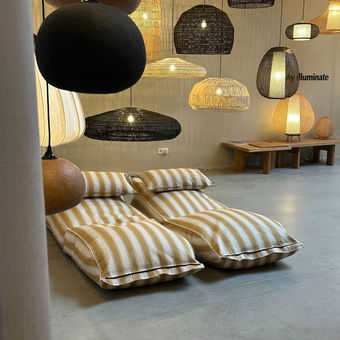 Twee loungebedden geplaatst onder een hemel van lampen