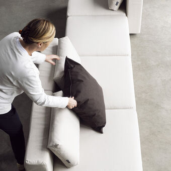Greta legt een kussen op de modulaire loungebank: de BRYCK NOMA.